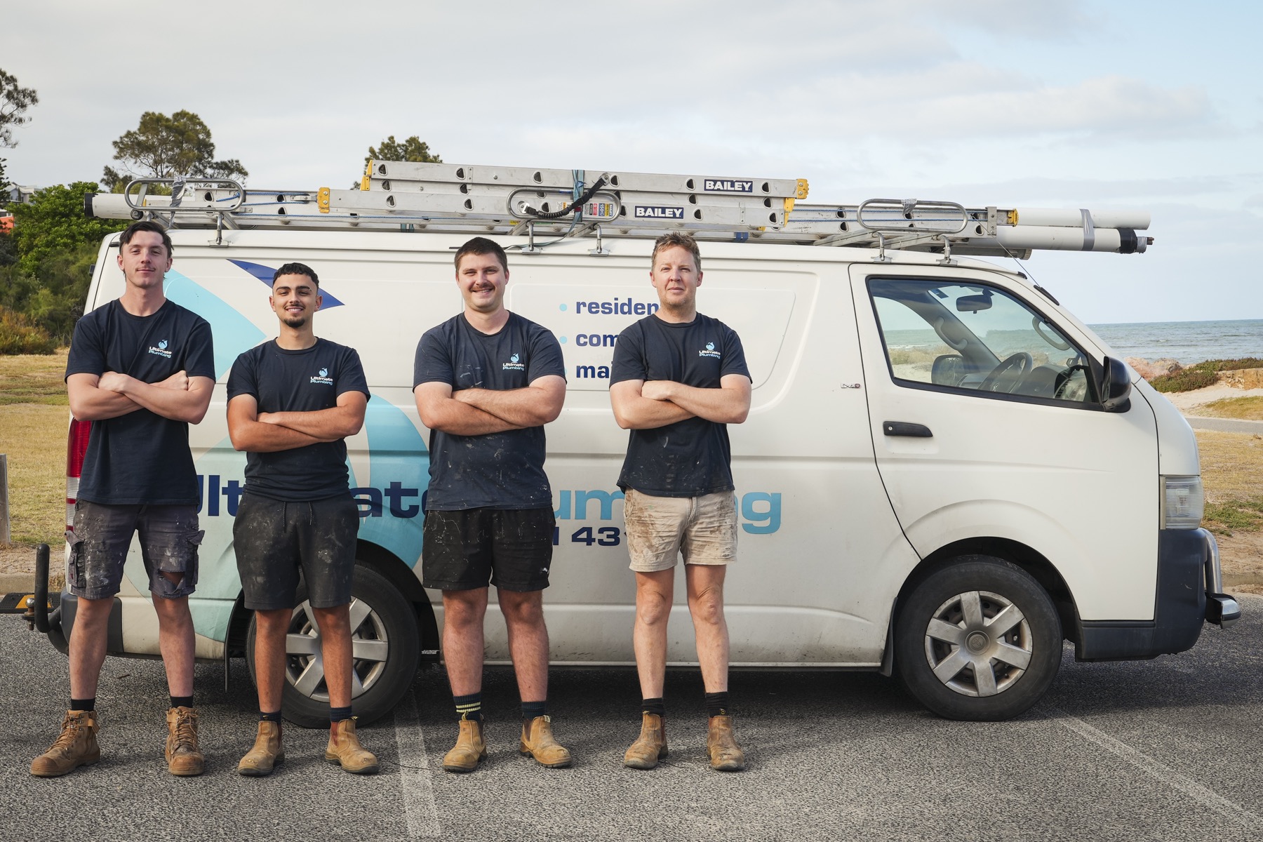 Ultimate Plumbing team standing beside a branded service van